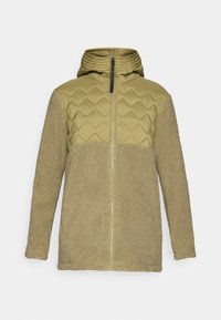 Beige fleecejakke med quiltet brystpanel og hette, hel foran glidelås og lange ermer, vist på en ensfarget bakgrunn.
