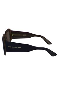 Ochelari de soare dreptunghiulari negri cu lentile închise, având o finisare lucioasă. Logo-ul Calvin Klein pe brate și accente metalice subtile.