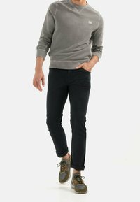 Grauer Sweatshirt mit Rippbündchen, schwarze Slim-Fit-Hose und grün/graue Sneakers. Das Outfit hat ein lässiges Design und praktische Materialien.