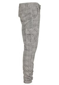 Pantalon cargo à carreaux gris et blanc avec plusieurs poches à rabat et des poignets élastiqués, vu de côté.