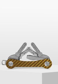 Multiverktyg med silverfärgade metallblad och handtag i gult kolfiber. Har flera verktyg inklusive en kniv och olika skruvmejslar.