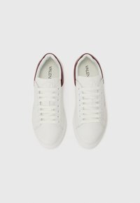 Witte leren sneakers met bordeauxrode accenten, voorzien van een ronde neus, platte rubberen zool en zes paar oogjes voor veters. "VALEN" logo aan de binnenkant.