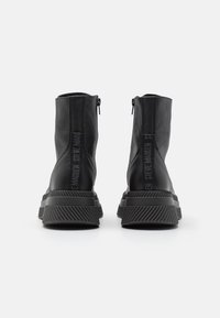 Botines negros de tobillo fabricados en cuero texturizado con una suela acanalada, que cuentan con un cierre de cremallera y una marca en la parte trasera.
