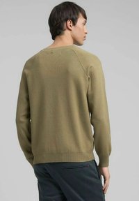 Olijfgroene trui van gebreide stof, met geribbelde boorden en zoom, een ronde hals en raglanmouwen, getoond van achteren.