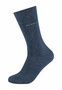 Calza alla caviglia di colore blu scuro, realizzata in tessuto morbido. Presenta una leggera texture e include un logo bianco sul lato esterno.