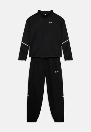 Zwart Nike trainingspak met lange mouwen, top met kwart rits en broek met elastische boorden, voorzien van witte Nike Swoosh-logo's en reflecterende stroken.