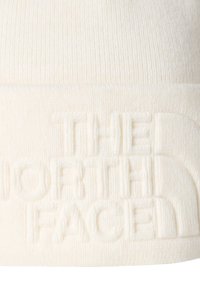 Biała dziana czapka beanie z teksturowanym logo "The North Face" na mankiecie, wykonana z miękkiego, ciepłego materiału o prążkowanym wzorze.