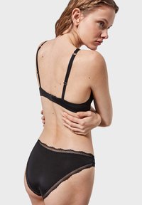 Set di lingerie nera con reggiseno a spalline regolabili e chiusura a gancio, abbinato a culotte a vita alta rifinite in pizzo.