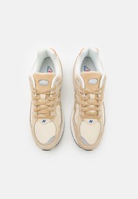 Baskets beiges en matériaux en daim et en maille. Présentent un bout arrondi, un design à lacets et des accents de logo bleu sur les côtés et la languette.