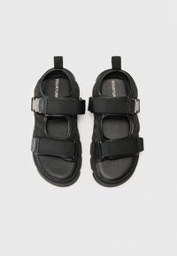 Black adjustable sandals with synthetic straps, velcro closures, open toe design, and textured rubber soles for grip.