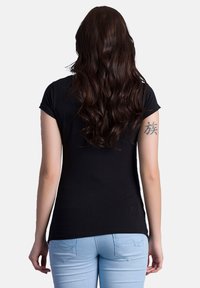 Black short-sleeve t-shirt with a fitted shape, smooth texture, and a crew neckline, paired with light blue jeans featuring decorative stitching.