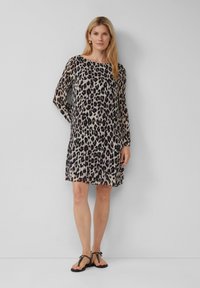 Leopardenprint jurk met lange mouwen, ronde hals, geplooide textuur en lengte boven de knie, gecombineerd met zwarte platte sandalen.