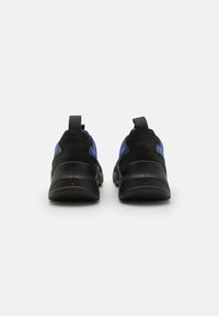 Des chaussures de sport noires et bleues avec un design enfilement, une semelle rembourrée, des accents en daim et des onglets contrastés au niveau du talon.