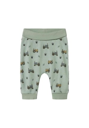 Weiche grüne Babypants mit elastischem Bund und Bündchen, versehen mit einem Muster aus kleinen blauen und gelben Traktoren sowie schwarzen Eimern.