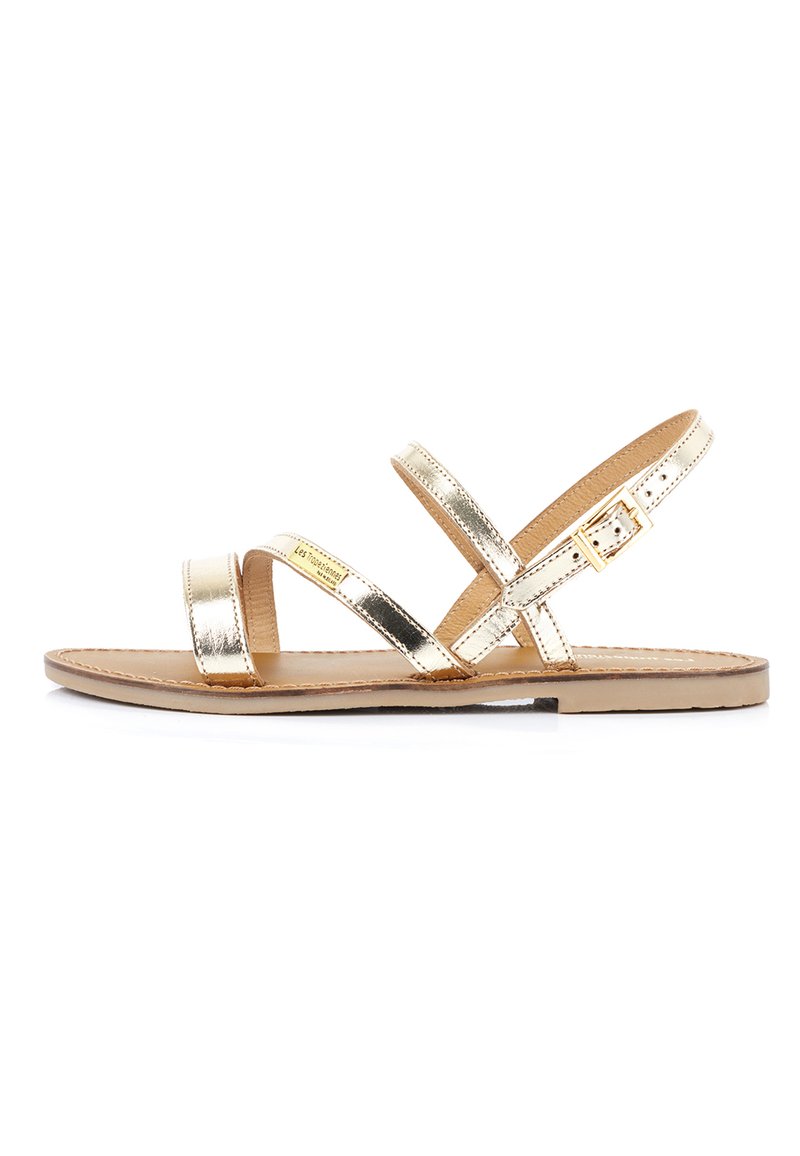 Sandali piatti metallici d'oro con due cinturini incrociati, cinturino alla caviglia regolabile con fibbia e soletta color cammello su suola piatta.