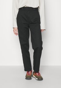 Pantalons noirs taille haute avec une coupe droite, en coton, présentant une texture lisse et une taille à passants pour ceinture.