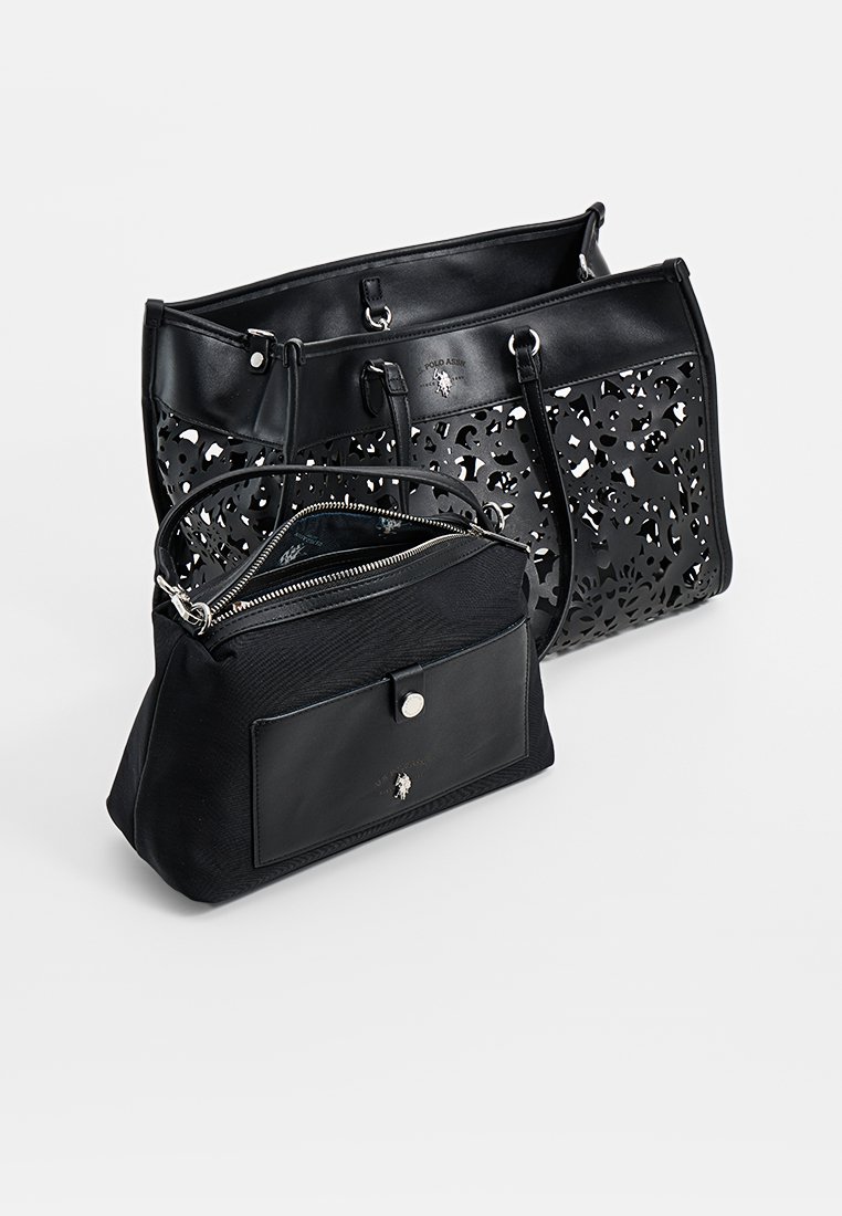 Dos bolsos negros: un tote más grande con un diseño floral cortado y un pouch más pequeño con cremallera y bolsillo delantero plano, ambos en cuero texturizado.