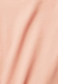 Pfirsichfarbener Stoff mit einer weichen, glatten Textur, der sanfte Falten und Kräuselungen zeigt. Leichter Baumwollmix, geeignet für verschiedene Kleidungsstücke.