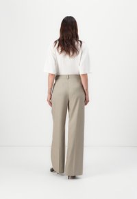 Beige wijde broek met een op maat gemaakte pasvorm en achterwaartse taille-tabellen. Gepaard met een witte top met korte mouwen. Gladde textuur, minimalistisch ontwerp.