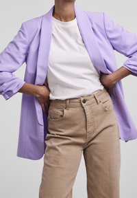 Ljuslila kavaj, avslappnad passform, med en mjuk textur. Matchas med en enkel vit t-shirt och ljusbeige högmidjade jeans.