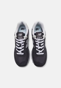 Crne New Balance 574 tenisice s sivim detaljima, od mrežastog i antilop materijala, bijelim vezicama, podstavljenim ovratnikom i reljefnom gumiranom potplatom.