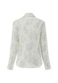 Camicia a maniche lunghe di colore chiaro con un delicato motivo floreale e farfalle. Realizzata in tessuto morbido, presenta un colletto classico e polsini con bottoni.