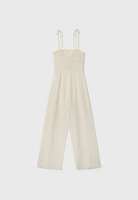 Combinaison sans manches de couleur crème avec corsage froncé, jambes larges et bretelles réglables à nouer, sur un fond clair uni.