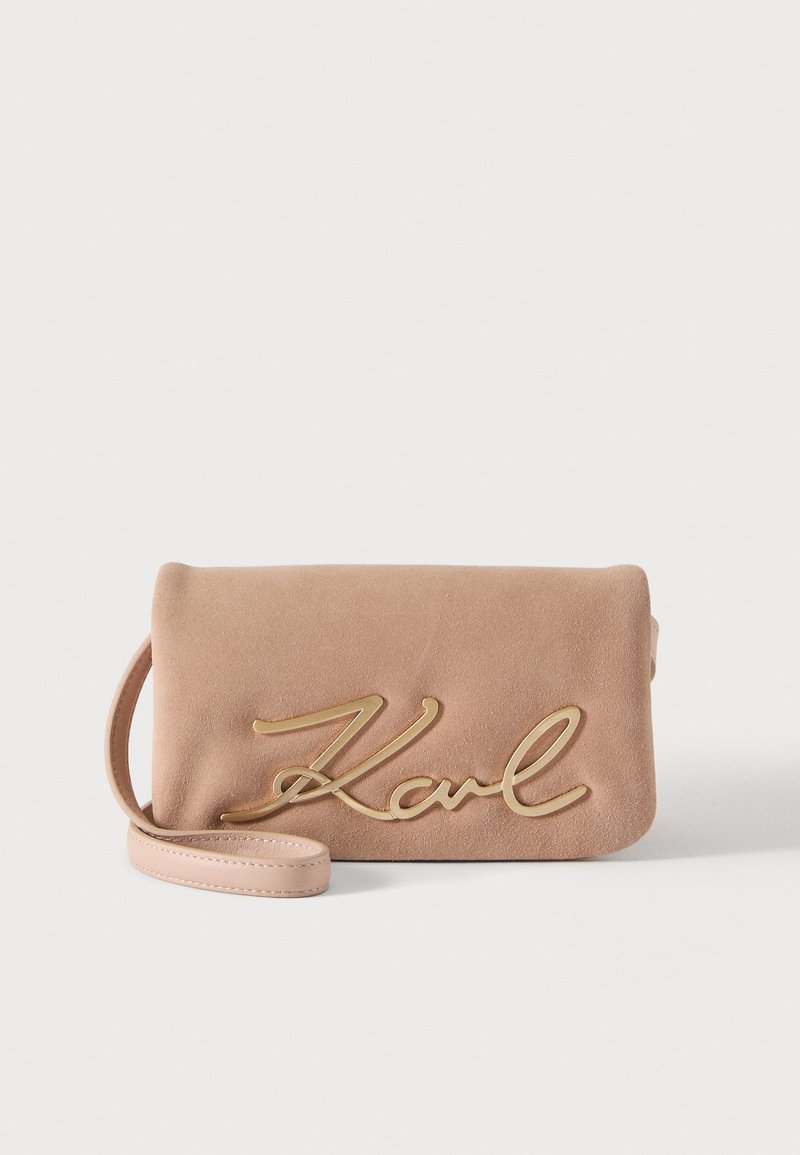 Μπεζ σουέντ τσάντα clutch με λουράκι για καρπό και μεγάλο χρυσό λογότυπο "Karl" σε γραμματοσειρά μπροστά.