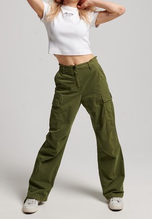 Olijfgroene cargobroek met een relaxte pasvorm, voorzien van meerdere voorzakken, een knoopsluiting en subtiele tekst op een witte cropped top.