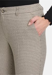 Lichtbeige en bruine geruite broek met een soepele textuur, voorzien van zijzakken en een standaard tailleband. Geschikt voor casual wear.