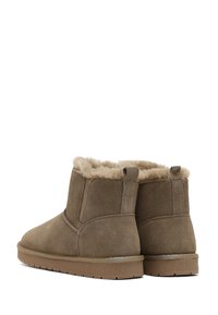 Bottines en suédine marron avec une doublure en fausse fourrure douce, présentant une semelle en caoutchouc plate et des détails de couture minimalistes. Pas de matériel ni de motifs visibles.