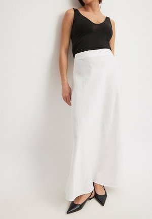 Top senza maniche nero abbinato a una gonna bianca a lunghezza caviglia realizzata in tessuto leggero. La gonna presenta una texture liscia e una silhouette svasata.