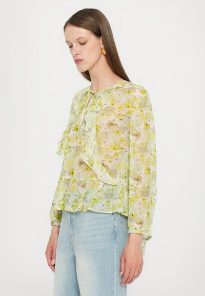 Floral blouse in sheer green fabric, featuring ruffles, a tie neckline, and long sleeves. Pattern includes light yellow and brown accents.