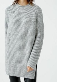 Pull en tricot gris avec texture côtelée, col rond, manches longues, fentes sur les côtés et coupe décontractée, fabriqué en mélange de laine douce.