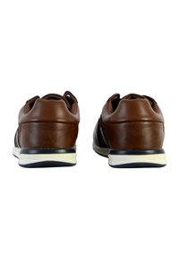Chaussures en cuir marron avec une finition texturée, une semelle blanche contrastante et un bout arrondi, présentant un design à enfiler et un branding minimal.