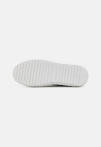 Suola di scarpa in gomma bianca con scanalature orizzontali testurizzate e un branding sottile. Il design è piatto con un tacco rotondo. Estetica pulita e minimalista.