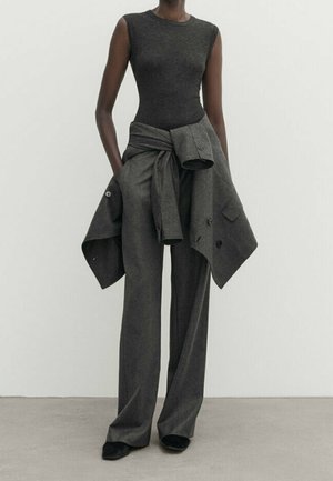 Grey sleeveless bodysuit paired with loose, high-waisted grey trousers. A matching jacket is tied at the waist. Smooth texture, minimal design.