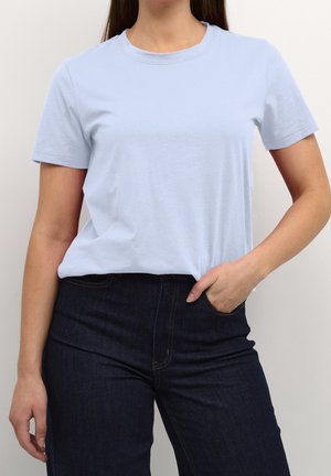 Jasnoniebieska bawełniana koszulka z okrągłym dekoltem i krótkimi rękawami, noszona z ciemnymi dżinsami, charakteryzująca się dopasowanym krojem i gładką fakturą.
