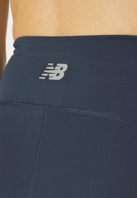 Tamsiai mėlyni leggingsai su lygiu paviršiumi, turintys subtilų šviesiai pilką logotipą. Juosmens juosta elastinga, kad užtikrintų komfortą ir palaikymą.