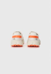 Lichte, crèmekleurige sneakers met een oranje band en buitenzool. Bevat textielmateriaal en een gebogen silhouet. Merkprint op de achterkant.