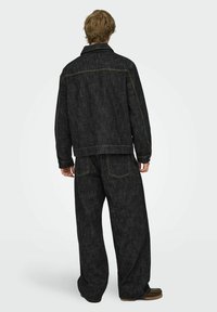 Must teksat kuldsete õmblustega denimpintsak ja laia lõikega püksid. Textuuriga materjal, vaba lõige ja klassikaline disain.