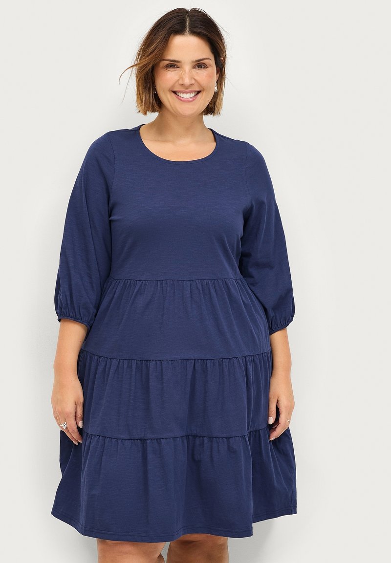 Abito a balze blu navy realizzato in tessuto morbido, con scollatura rotonda e maniche a tre quarti a sbuffo, con cuciture arricciate alle balze.
