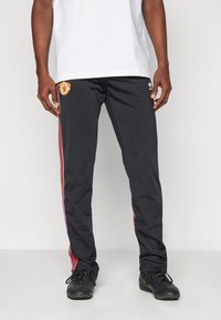 Black athletic pants with red stripes along the sides, featuring a logo on the upper left leg. Made of smooth, lightweight material.