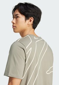 Olive green short-sleeve t-shirt featuring a white line design on the back, with a crew neckline and soft, textured fabric.