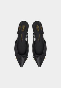 Μαύρα φλατ παπούτσια slingback με μυτερή μύτη, φιόγκους και χρυσά λουράκια με αγκράφα, με επενδυμένα εσωτερικά πέλματα με σήμανση "Clarks Signature".