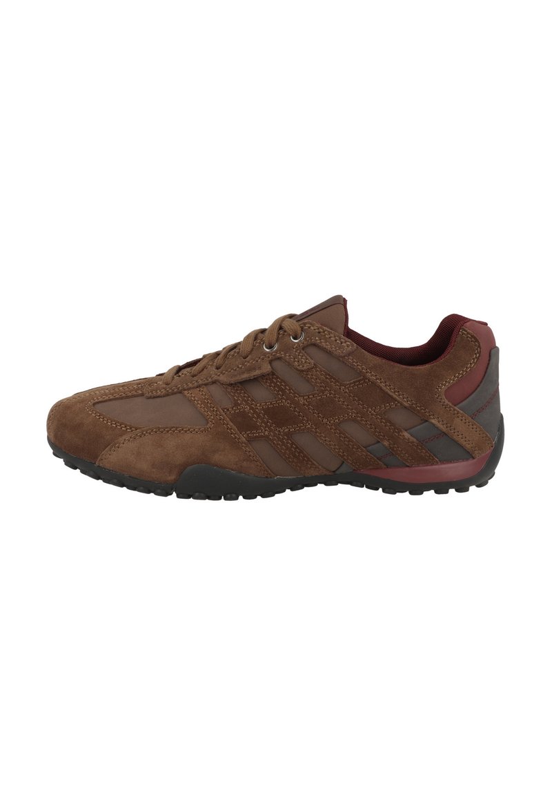 Scarpa sportiva in suede marrone con accenti in mesh, suola in gomma e dettagli rossi sul tallone; presenta lacci e una superficie superiore testurizzata.