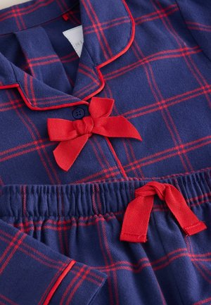 Námořnická látková pyžamová souprava s červeným kostkovaným vzorem, červenými lemy a akcenty. Obsahuje límeček a mašle nahoře a na pase, měkká textura.