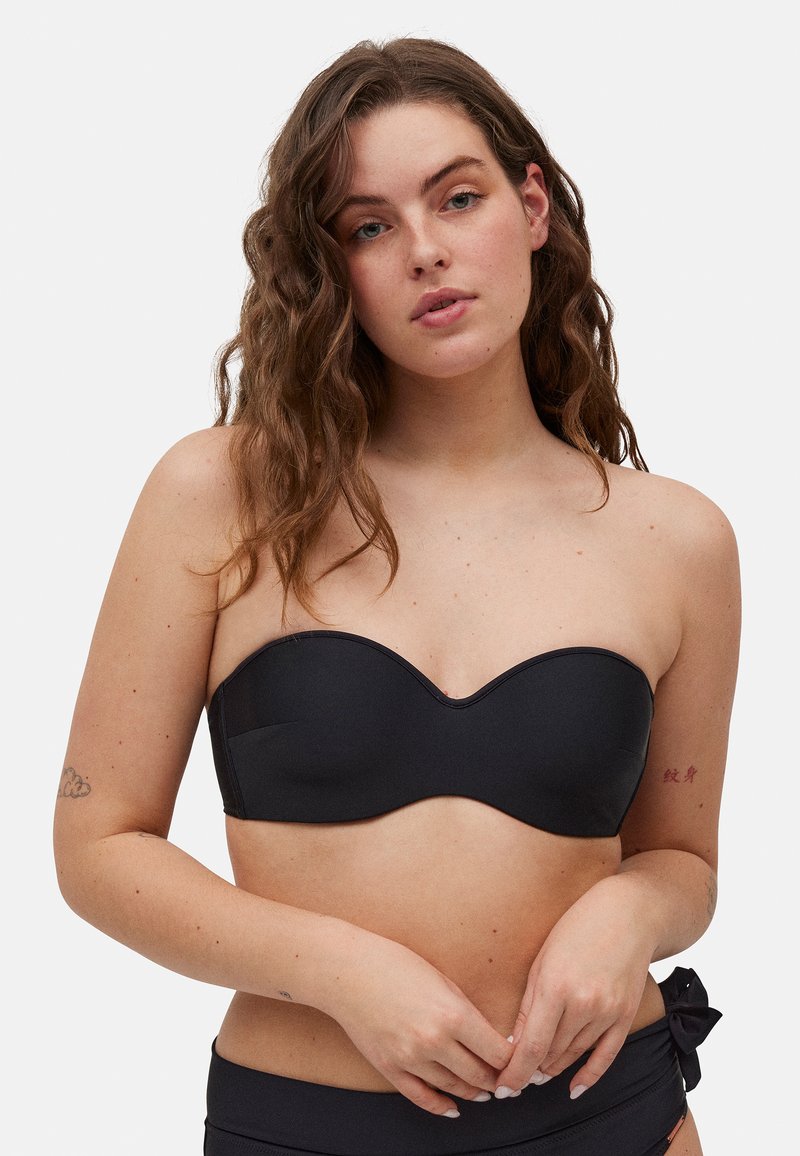 Top de bikini negro sin tirantes con una costura ondulada, textura suave y sin herrajes. Combinado con una parte inferior a juego que presenta un detalle de lazo.