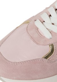 Sneaker in suede rosa con eleganti dettagli dorati, lacci bianchi e un pannello in tessuto liscia. Punta arrotondata con dettagli testurizzati lungo i bordi.
