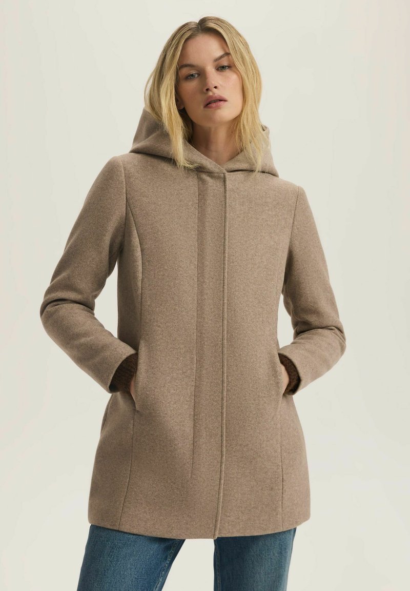 Beżowy płaszcz z wełny z kapturem, o dopasowanym kroju, przodzie pionowych szwów oraz kieszeniach; teksturowany materiał o miękkim wyglądzie.